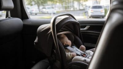 Ein Baby liegt in einem Kindersitz auf der Rückbank eines Autos.