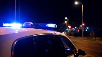 Weißes Polizeifahrzeug mit blauem Blaulicht auf einer nächtlichen Straße