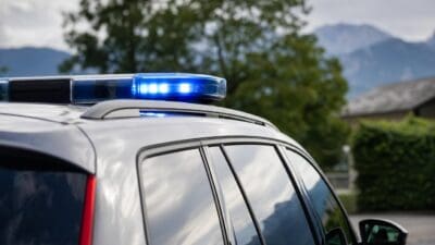 Nahaufnahme eines blauen Blaulichts auf dem Dach eines silbernen Fahrzeugs mit Bergen im Hintergrund
