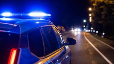 Polizeifahrzeug mit blauem Blaulicht und rotem Rücklicht auf nächtlicher Straße