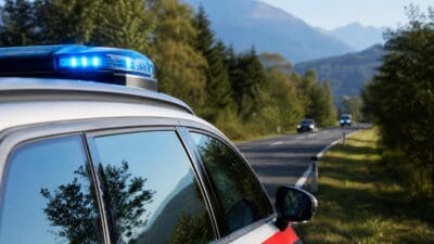Polizeifahrzeug mit blauem Blaulicht auf einer Landstraße in den Bergen