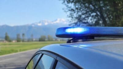 Nahaufnahme eines leuchtenden blauen Blaulichts auf dem Dach eines Polizeifahrzeugs mit Bergen im Hintergrund