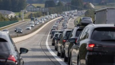 Lange Kolonne von Autos mit Dachboxen und leuchtenden Bremslichtern auf einer Autobahn