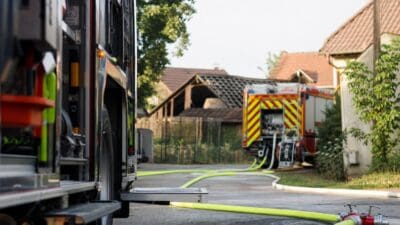 Feuerwehrfahrzeuge und ausgerollte Schläuche vor einer beschädigten Scheune in Zellerndorf