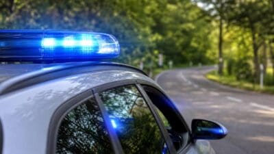 Nahaufnahme eines blauen Blaulichts auf dem Dach eines Polizeifahrzeugs an einer Landstraße.