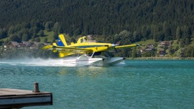 Ein gelbes Löschflugzeug vom Typ Air Tractor nimmt Wasser am Weissensee auf