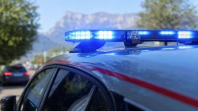 Nahaufnahme des leuchtenden Blaulichtbalkens auf einem Polizeifahrzeug mit Bergpanorama im Hintergrund