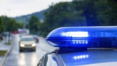 Nahaufnahme eines aktivierten blauen Blaulichts auf einem Polizeifahrzeug bei Dämmerung