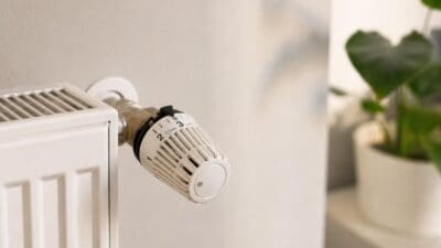 Weißer Heizkörper mit Thermostatventil auf Stufe drei und Schneeflockensymbol