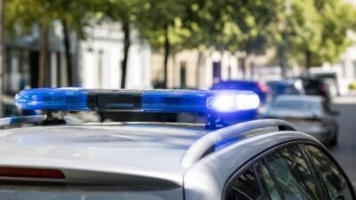 Blaues Blaulicht auf dem Dach eines silbernen Polizeifahrzeugs in einer Straße