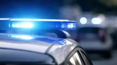 Nahaufnahme eines blauen Blinklichts auf dem Dach eines Polizeifahrzeugs mit unscharfem Hintergrund