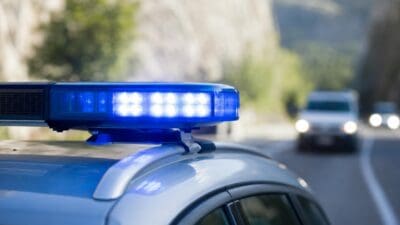 Blaues Blaulicht auf dem Dach eines Polizeifahrzeugs auf einer Bergstraße