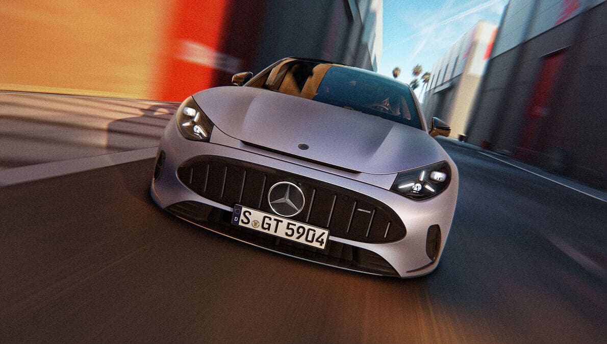 Silbernes Mercedes-AMG GT Coupé mit beleuchteten Scheinwerfern fährt schnell auf einer Straße mit modernen Gebäuden.