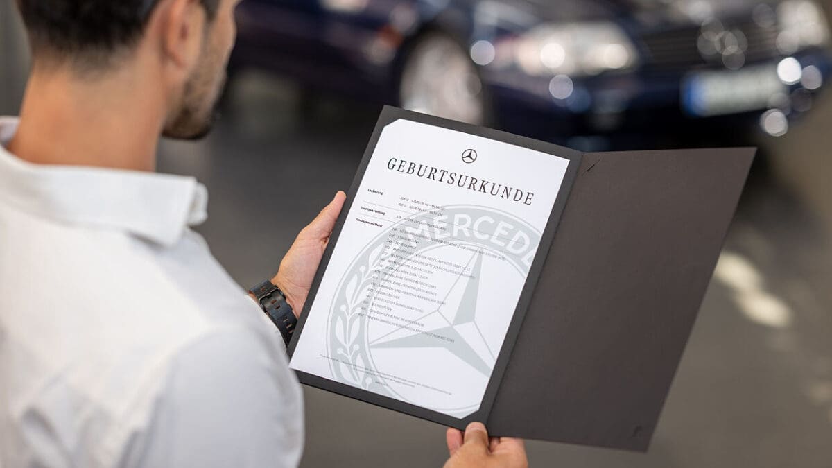 Ein Mann hält eine geöffnete Mappe mit der Mercedes-Benz Geburtsurkunde in der Hand.