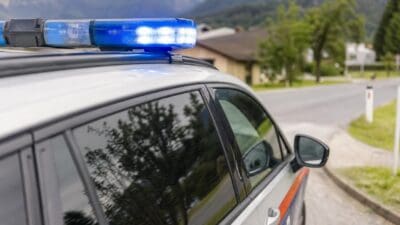 Polizeifahrzeug mit Blaulicht vor Häusern und Bergen in Innsbruck