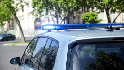 Polizeifahrzeug mit leuchtendem blauen Blaulicht auf dem Dach in einer Straße