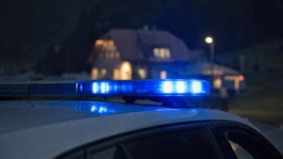 Blaues Blinklicht auf dem Dach eines Einsatzfahrzeugs vor einem Haus bei Nacht