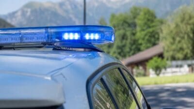 Blaues Blaulicht eines Polizeifahrzeugs leuchtet vor einer Berglandschaft