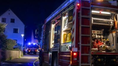 Rotes Feuerwehrfahrzeug mit geöffneten Einsatzfächern und Beleuchtung bei Nacht