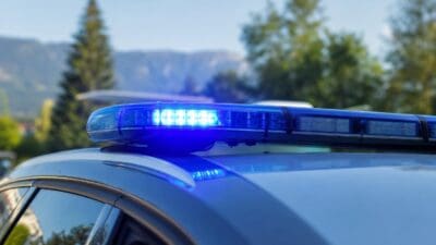Nahaufnahme eines blauen Blaulichts auf dem Dach eines Polizeifahrzeugs mit unscharfem Hintergrund.