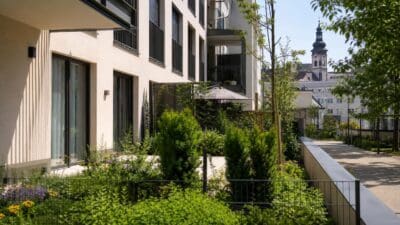 Modernes Wohngebäude mit Balkonen, großen Fenstern und begrünter Gartenanlage