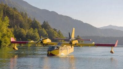 Gelbes Löschflugzeug mit roten Tragflächen auf dem Wasser des Weißensees