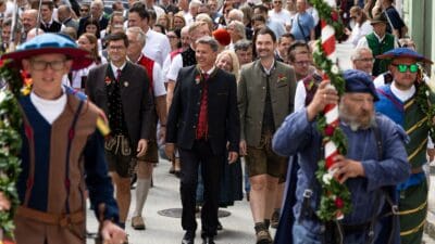 Männer in Tracht mit geschmückten Stangen beim Festumzug durch Bleiburg