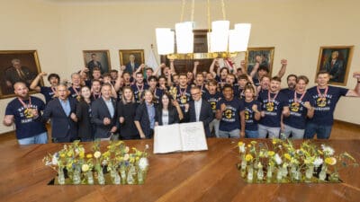 Gruppe jubelnder American-Football-Spieler der Graz Giants und Politiker im Grazer Rathaus mit offenem Buch