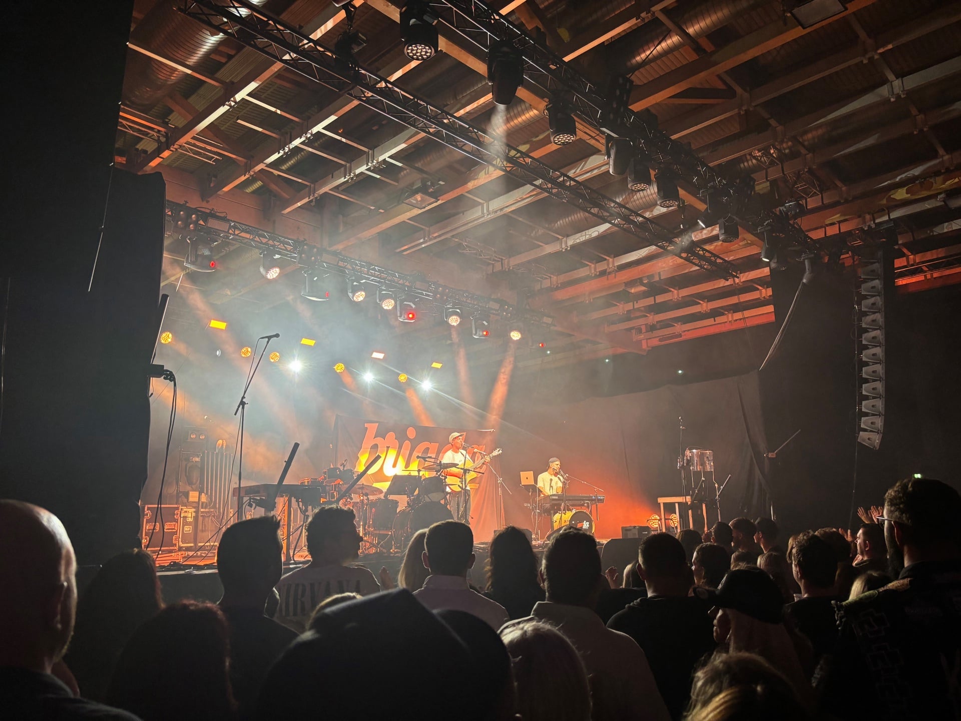 Musiker spielen auf einer beleuchteten Bühne vor dem Publikum in der Messehalle Klagenfurt.