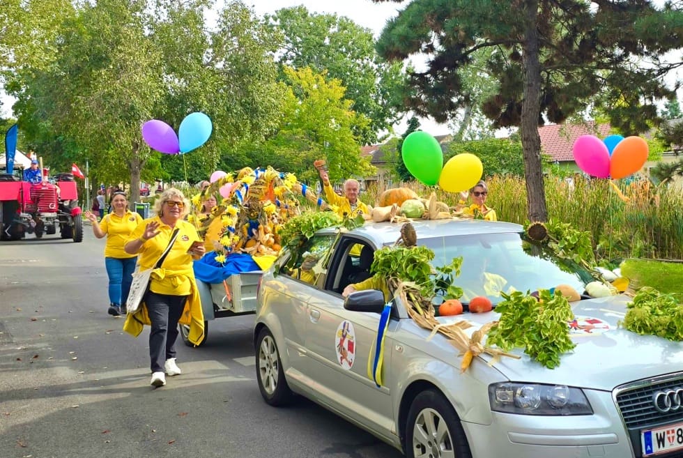 Mit Gemüse, Pflanzen und bunten Luftballons geschmücktes Auto bei einem Festumzug