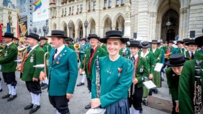 Eine Gruppe von Blasmusikern in traditionellen grünen Uniformen spielt vor dem Rathaus in Wien.