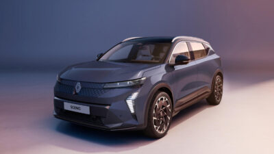 Grauer Renault Scenic E-Tech Electric SUV in Front-Dreiviertelansicht mit beleuchteten Scheinwerfern