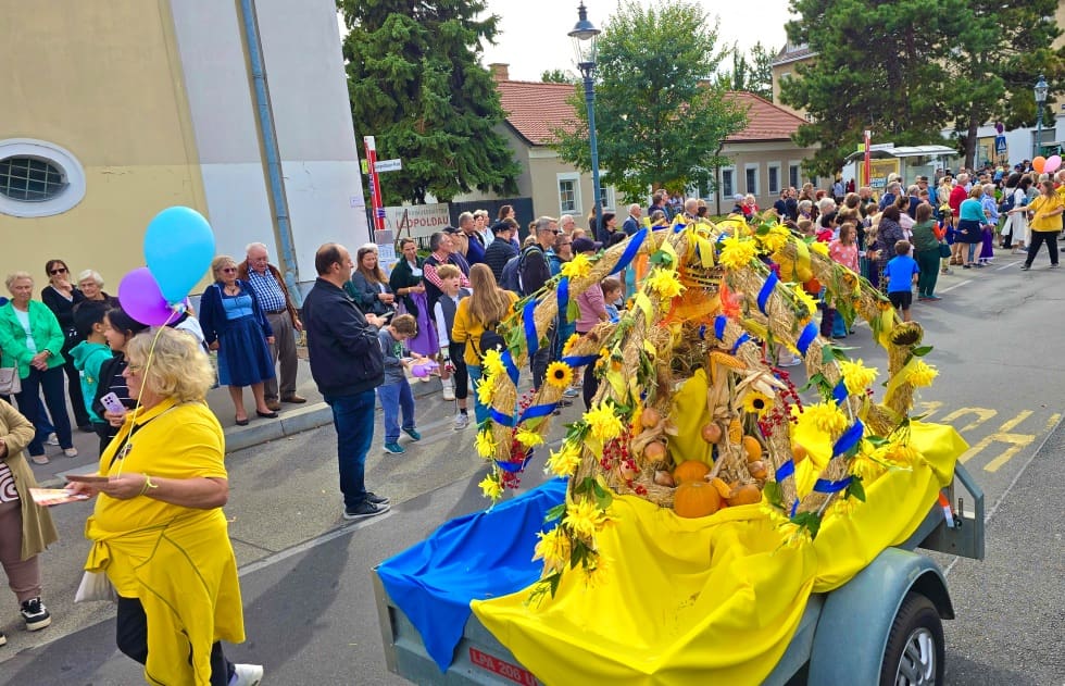 Geschmückter Erntedankwagen mit Sonnenblumen und Kürbissen auf einer belebten Straße