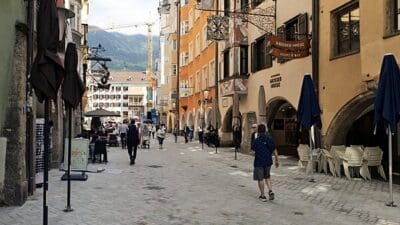 Belebte Fußgängerzone in der Altstadt von Innsbruck mit historischen Gebäuden und Bergpanorama