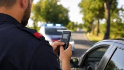 Ein Polizist in Uniform hält ein Handgerät zur Messung des Atemalkohols während einer Verkehrskontrolle.