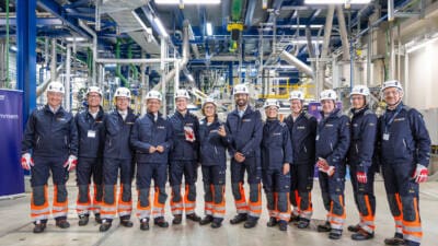 Menschen in Schutzkleidung stehen in einer Industrieanlage.