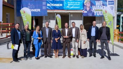 Gruppe von Personen vor einer Baustelle mit Werbebannern am Campus Frau Hitt in Innsbruck