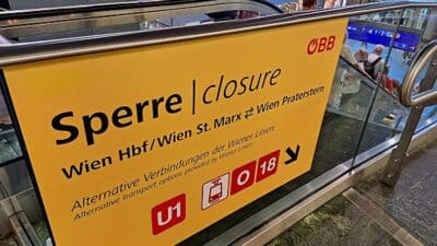 Gelbes ÖBB-Schild an einer Rolltreppe mit Hinweis auf die Sperre der Wiener S-Bahn-Stammstrecke und Alternativen.