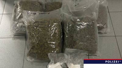 Transparente Plastikbeutel mit Cannabiskraut und Kokain auf einem Fliesenboden