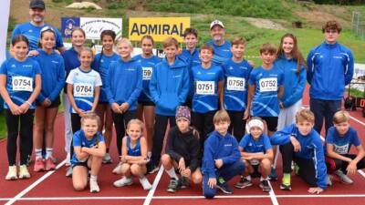 Gruppe junger Athleten und Betreuer des LC Villach in blauen Sportkleidern auf einer Laufbahn