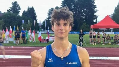 Junger Leichtathlet Matthias Altenberger in blauem LC Villach Trikot mit erhobener Faust auf der Laufbahn.