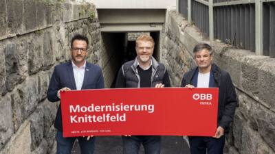 Drei Vertreter halten eine ÖBB-Tafel vor dem Personendurchgang Claudius-Höhle in Knittelfeld.