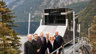Gruppe von Personen vor der neuen Salzbergbahn Hallstatt mit See und Bergen im Hintergrund