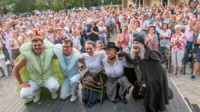 Vier Schauspieler in Kostümen posieren vor applaudierendem Publikum beim Theaterwagen in Spittal.