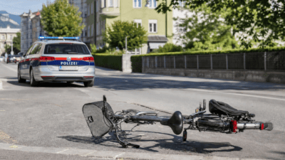 Umgestürztes Fahrrad liegt auf der Straße vor einem Polizeiauto in Innsbruck.