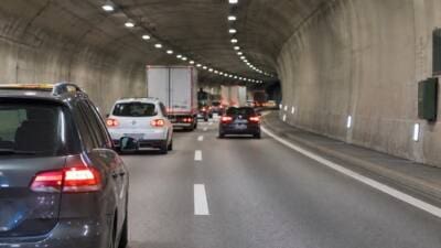 Fahrzeuge mit leuchtenden Rücklichtern fahren in einem beleuchteten Straßentunnel