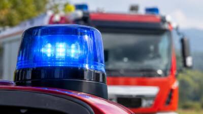 Blaues Warnlicht auf einem Feuerwehrfahrzeug, dahinter unscharf ein rotes Einsatzfahrzeug