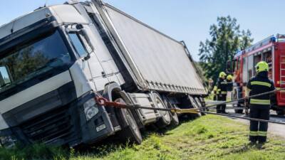 Gekippter weißer Lkw-Anhänger wird von Feuerwehrleuten mit Seilwinden aufgerichtet