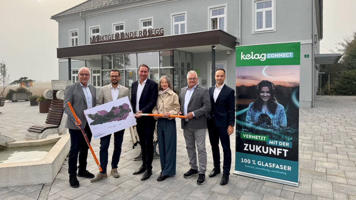 Menschen präsentieren vor dem Gemeindeamt Rosegg eine Karte und ein orangefarbenes Kabel.