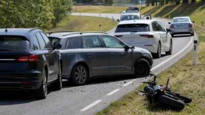 Mehrere beschädigte Autos und ein Motorrad nach einem Verkehrsunfall auf einer Landstraße.